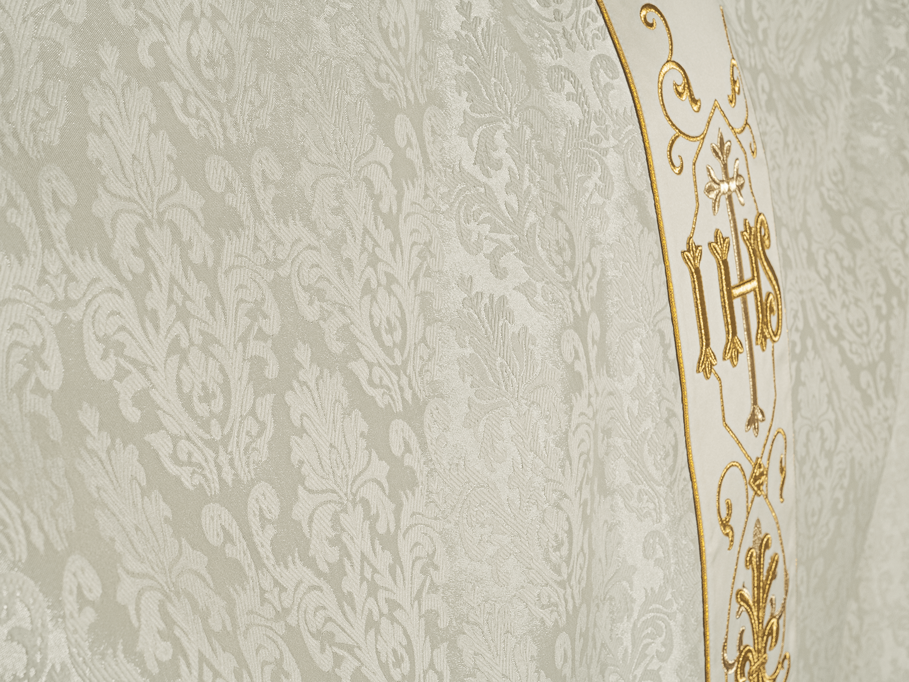 Ornat ecru haftowany na ozdobnej tkaninie z symbolem IHS