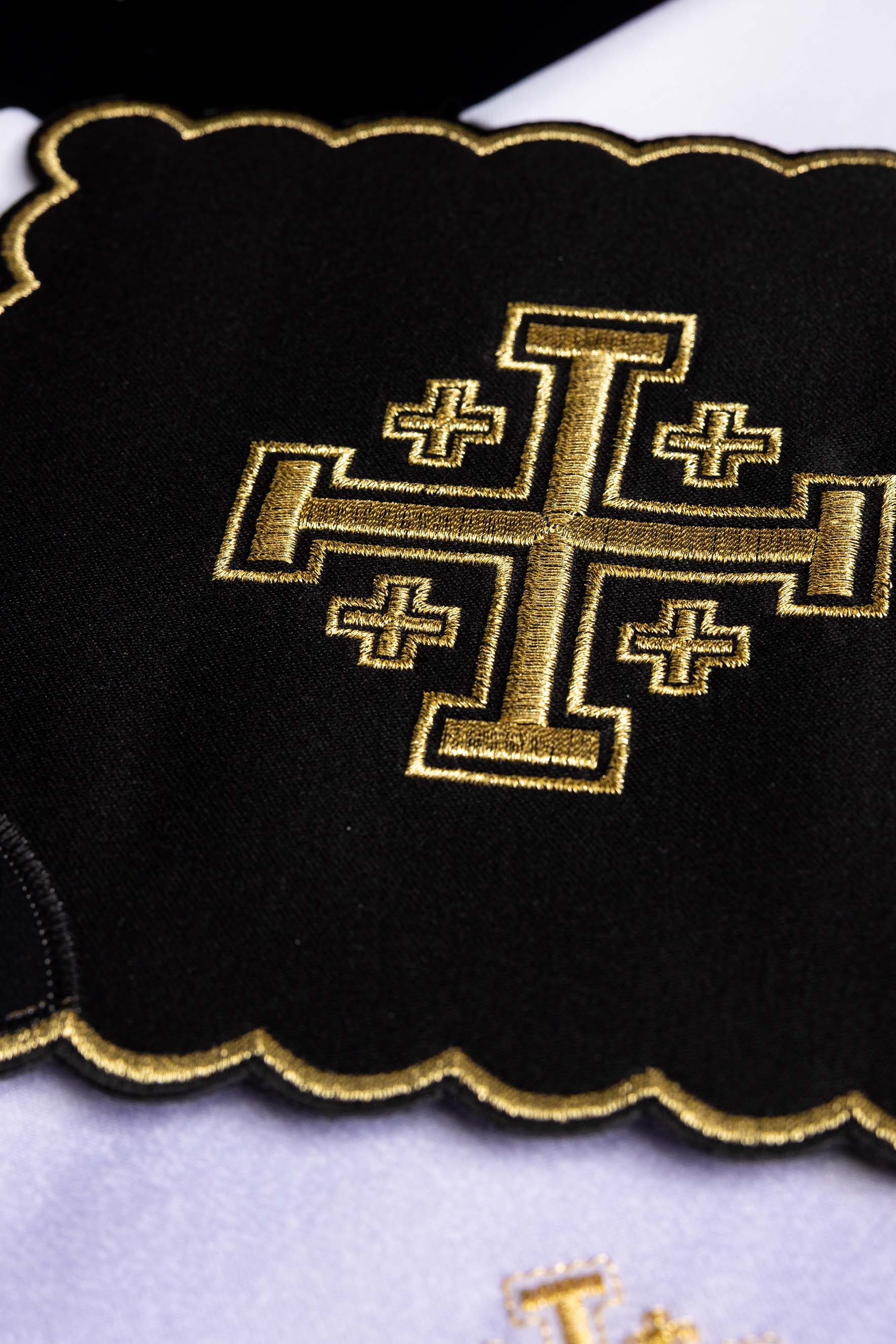 Czarna palka ze złotym haftem Krzyża Jerozolimskiego — detal haftu i falistej krawędzi ze złotym konturem.